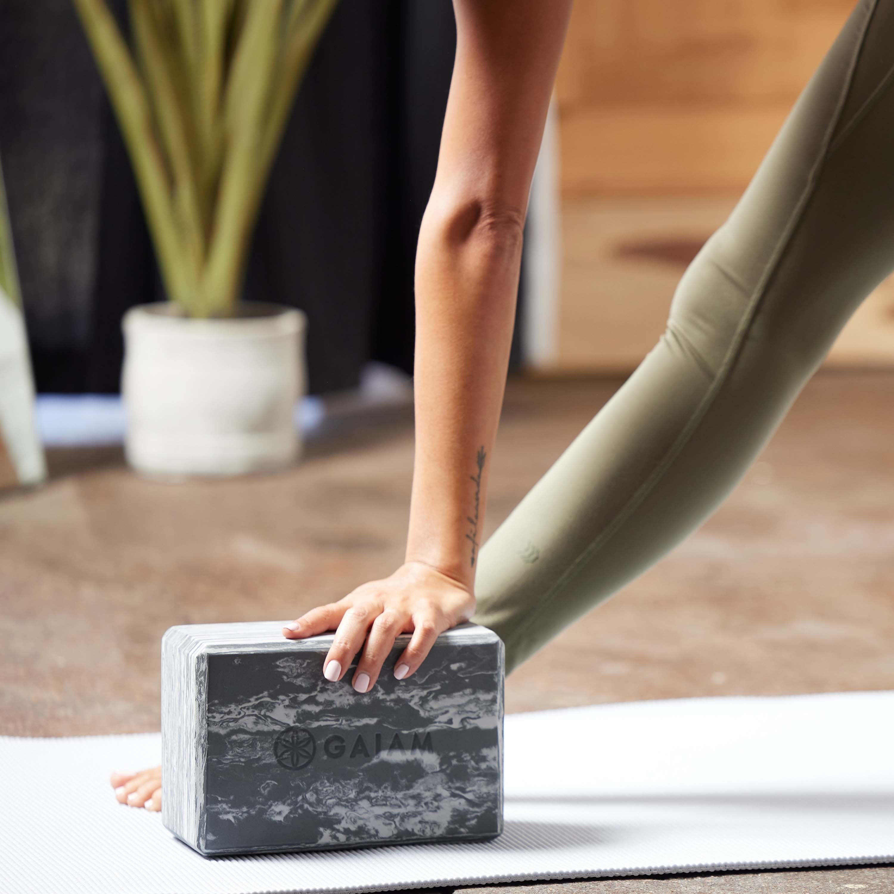 Up close image of person in forward bend with one hand on  Marbled Yoga Block